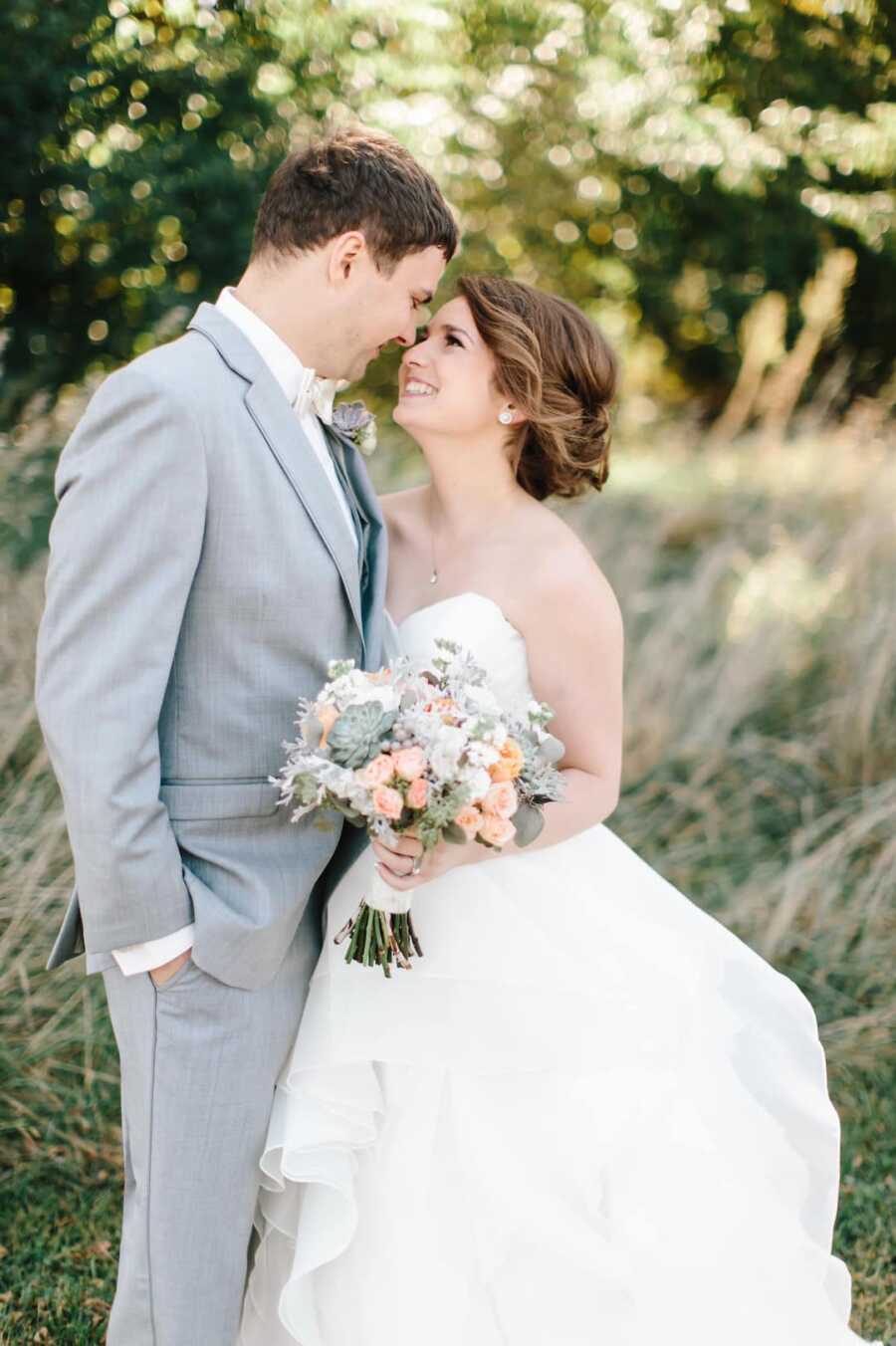 Husband and wife in wedding attire look at each other lovingly.