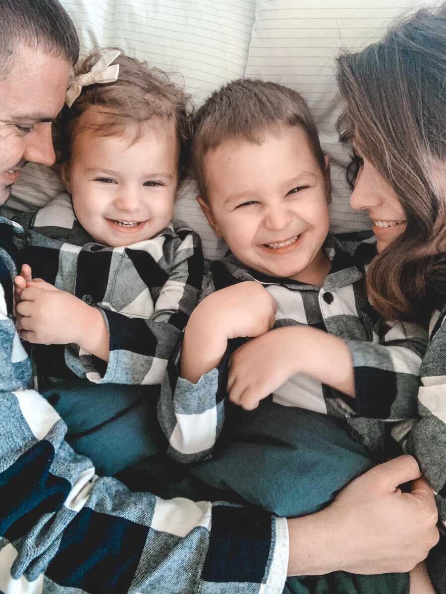 Parents snuggle two children while all wearing matching flannel shirts.