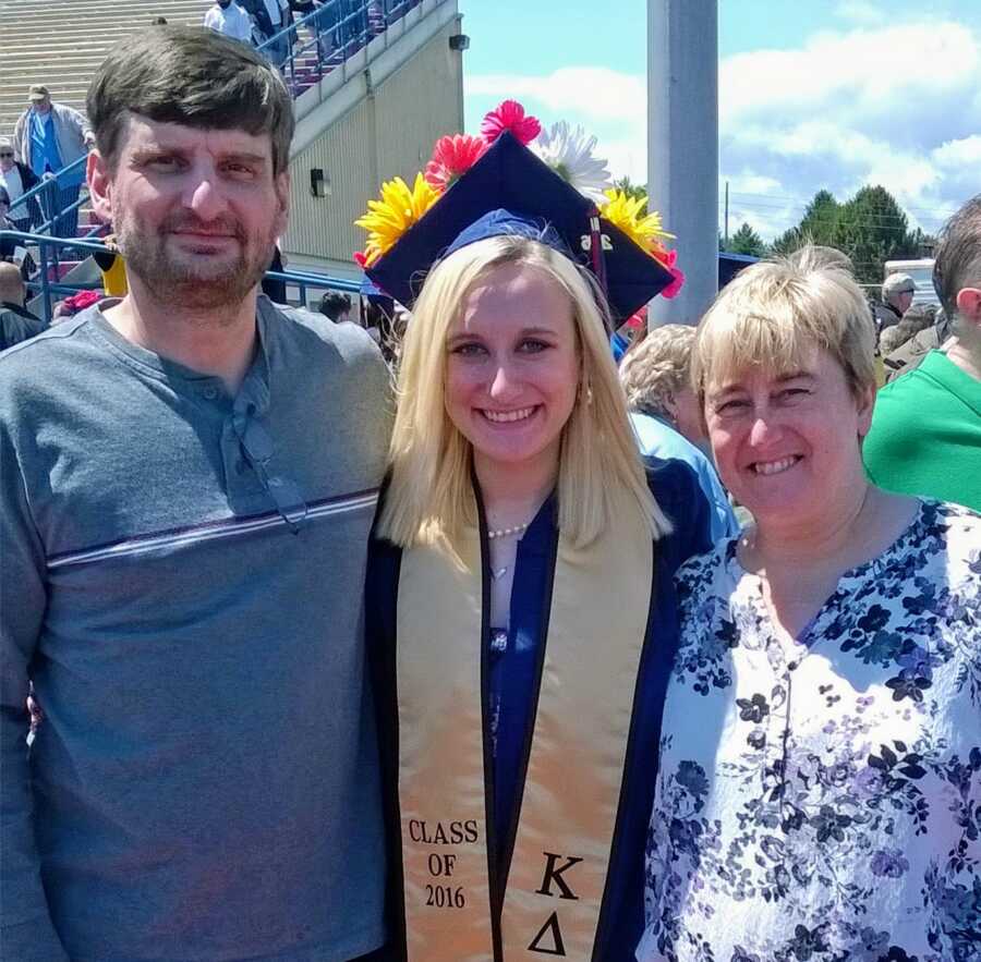 alcoholic in cap and gown with parents at college graduation