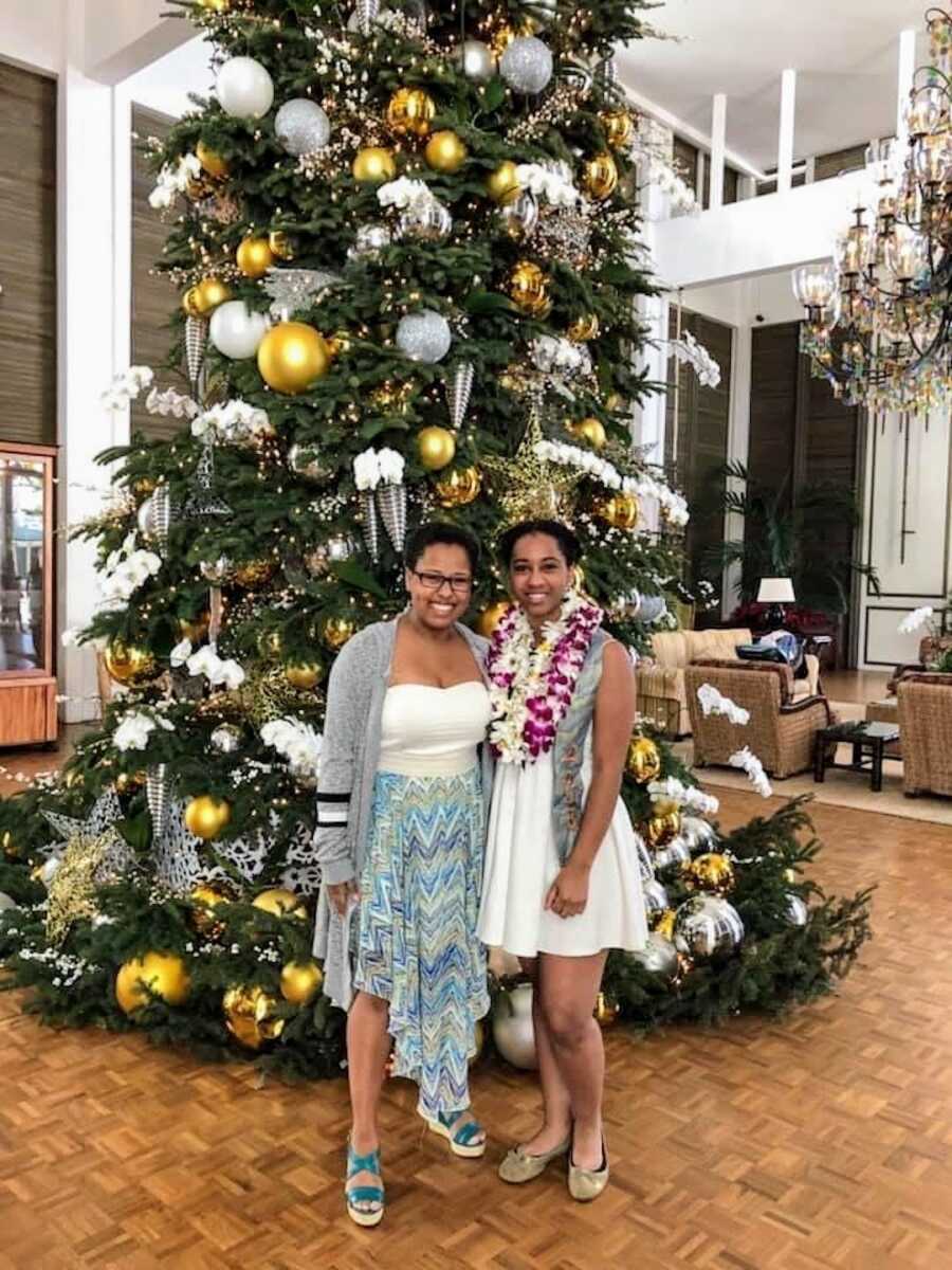 two friends smiling by a Christmas tree