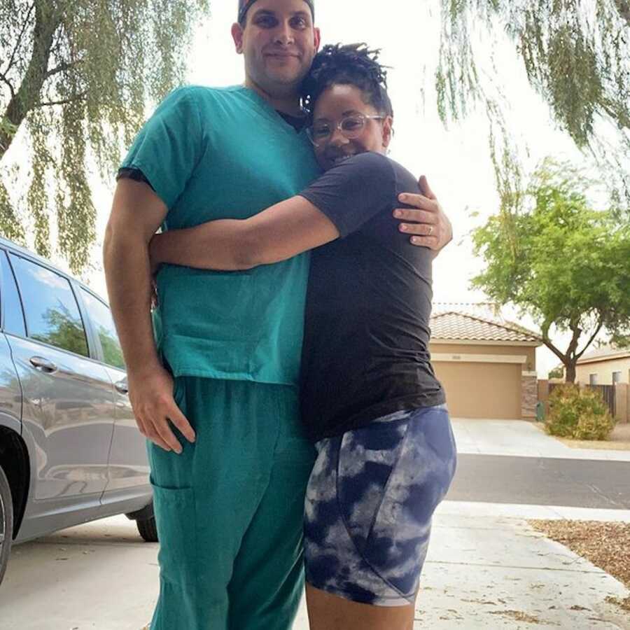 woman embracing a man in hospital scrubs