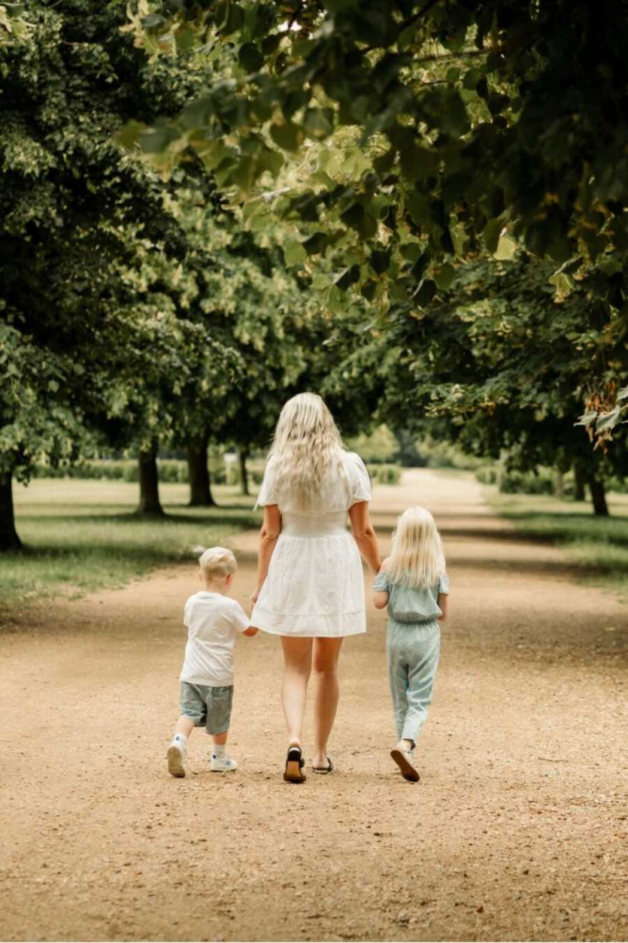 mom and her kids walking away from the camera in a park