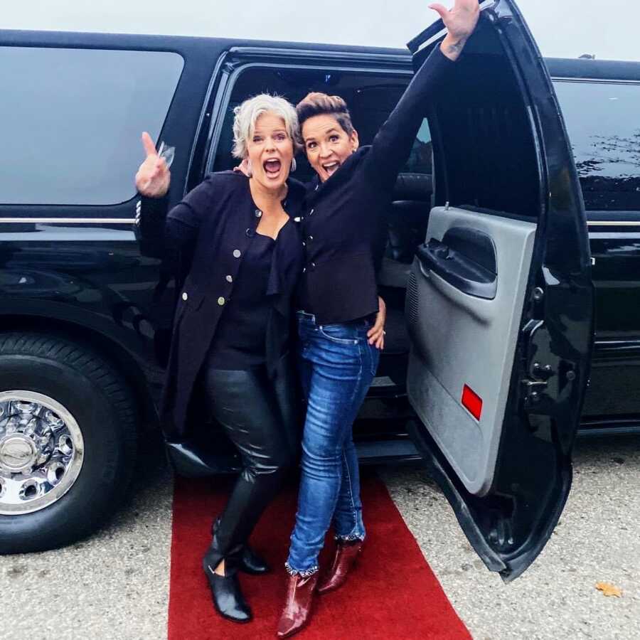 Two gay women outside limo on wedding day