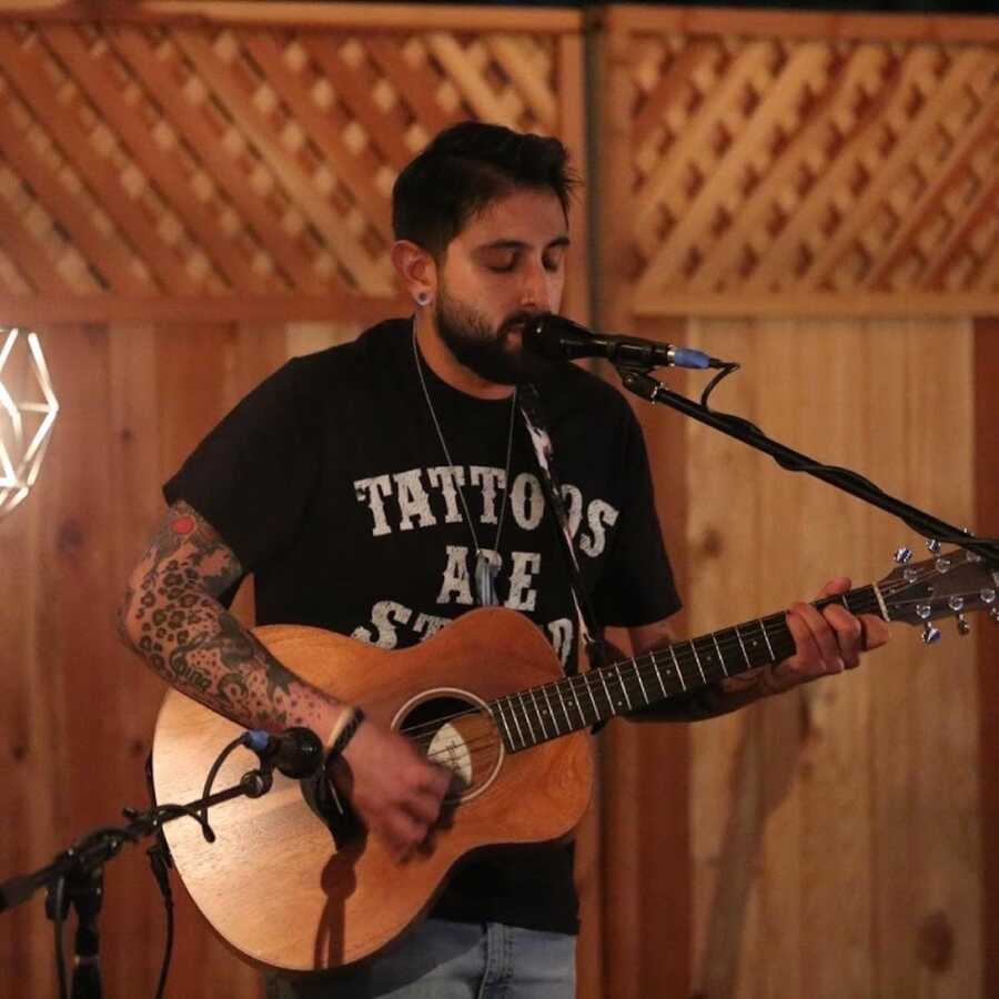 Man playing acoustic guitar and singing into microphone