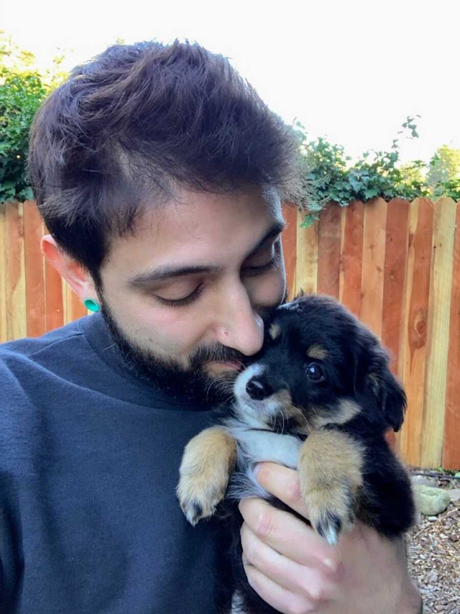 Man holding puppy up to his face and smiling