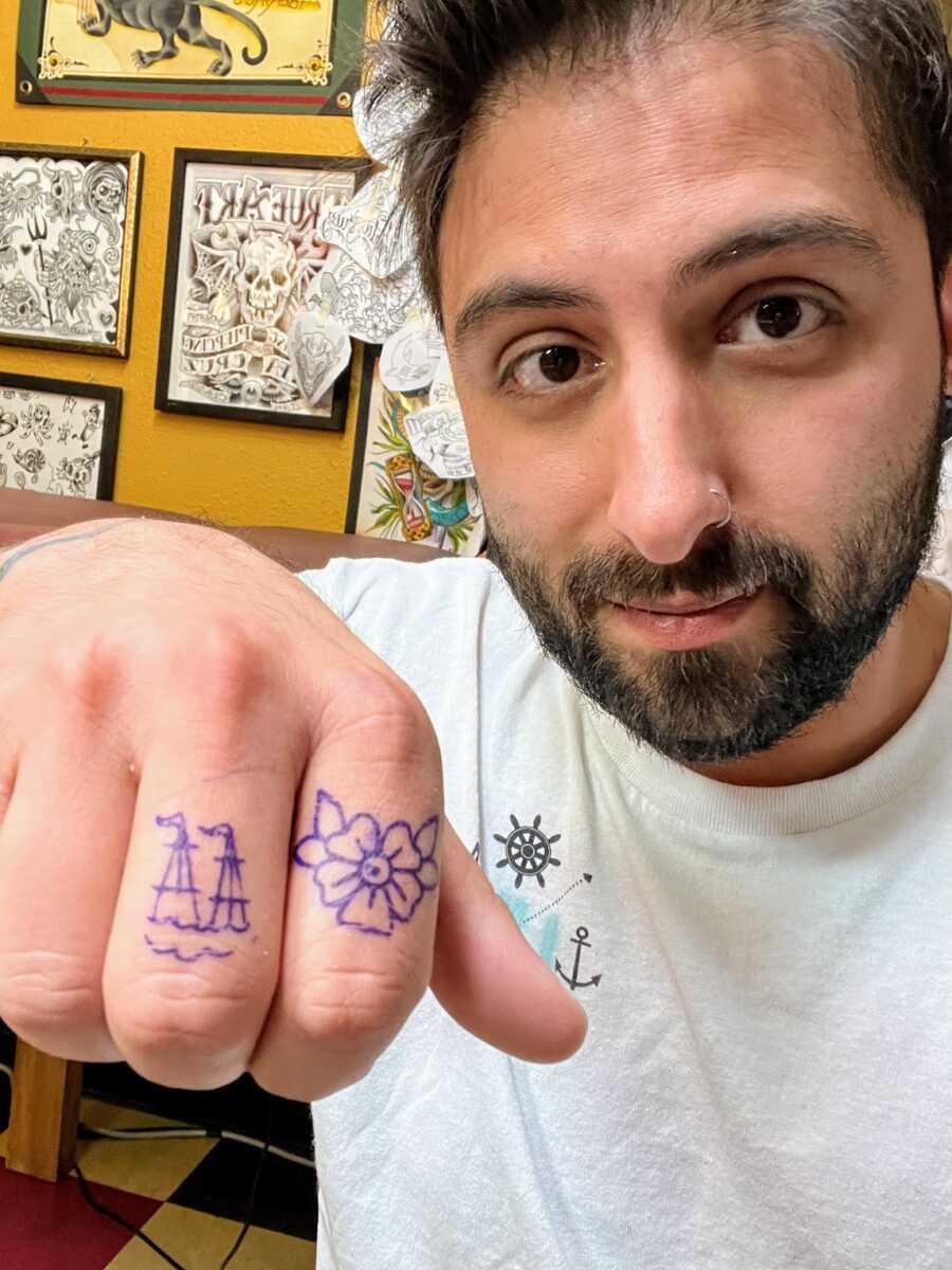 Man showing off finger tattoos