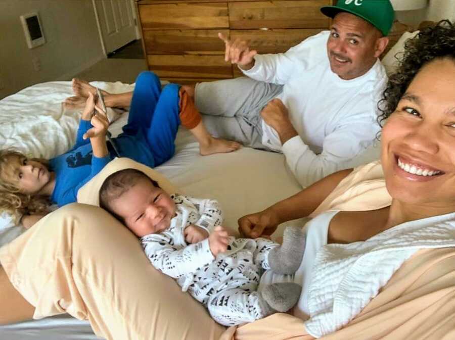 Mother, Father, and two sons lying on bed together