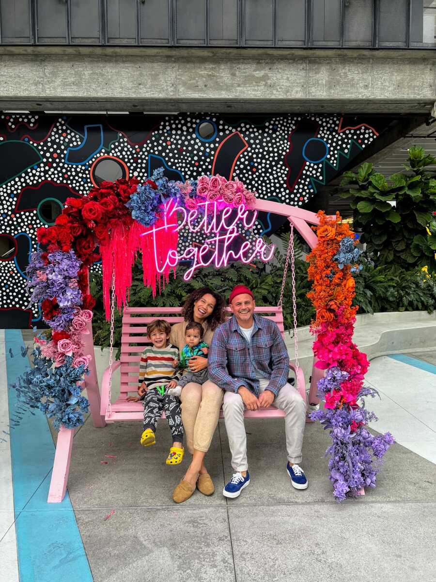 Family of four sitting on pink, hanging bench