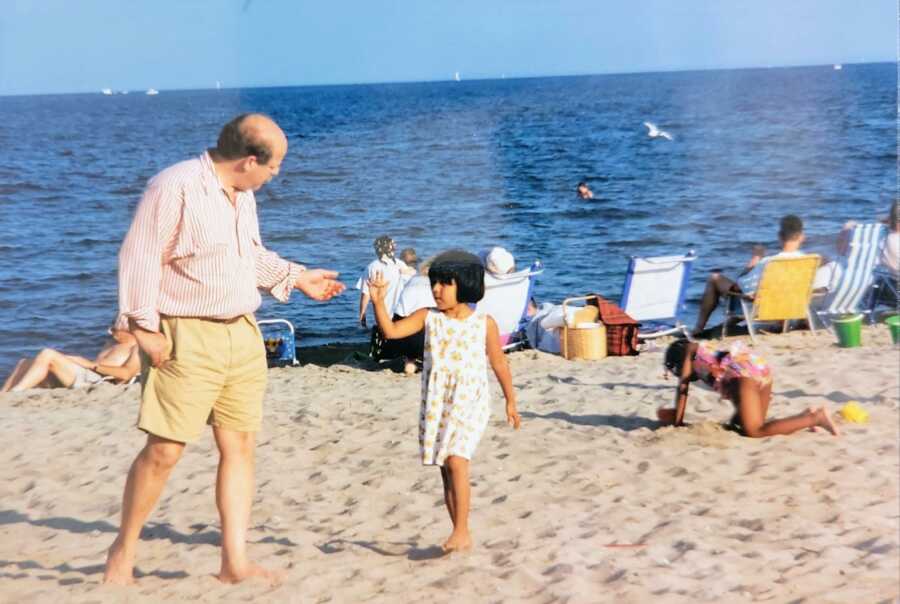 Father and adopted daughter standing on beach