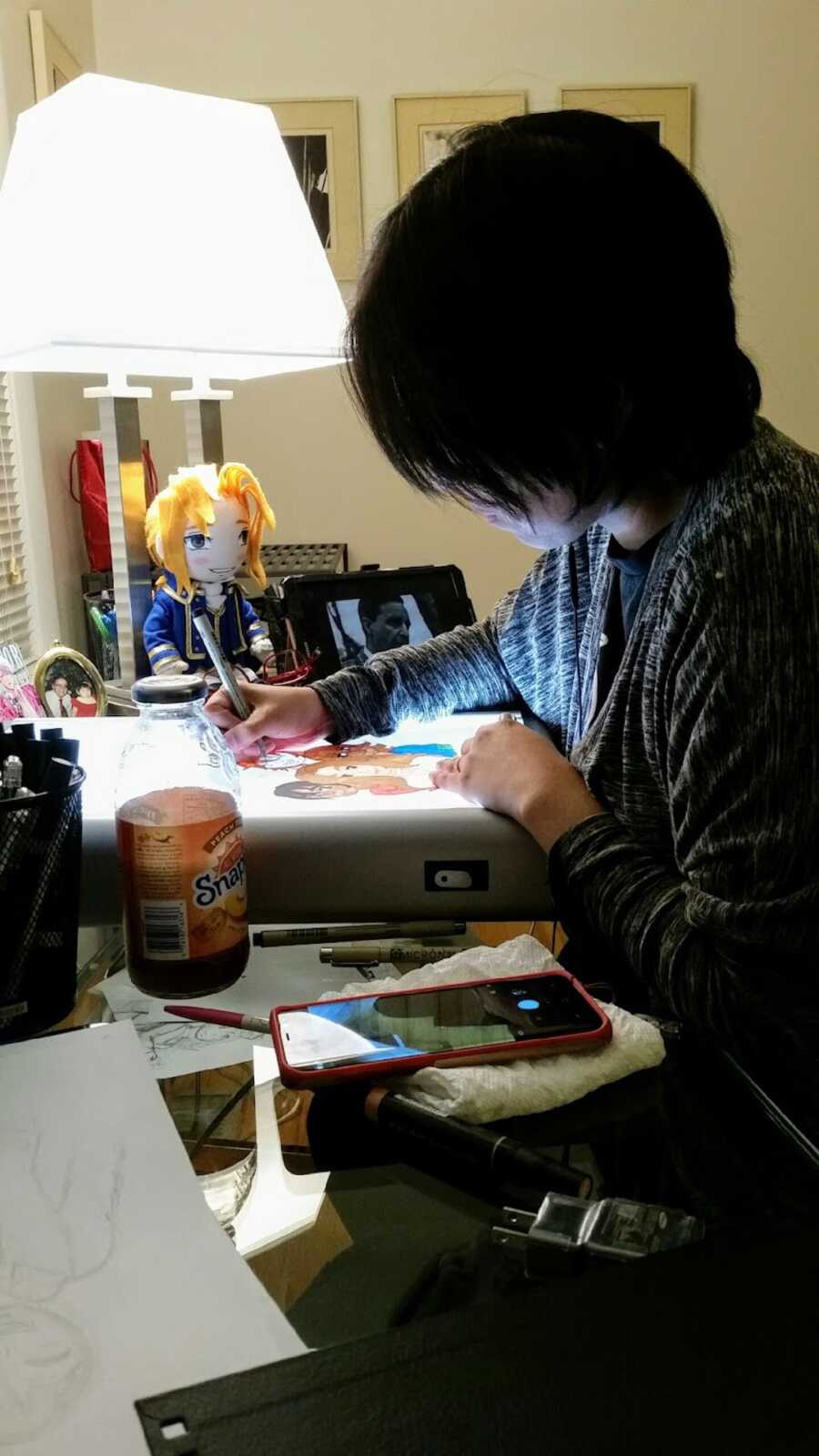 Young woman working on a drawing at a cluttered desk