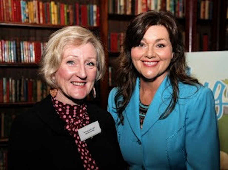 Two women standing at a book event in front of bookshelves