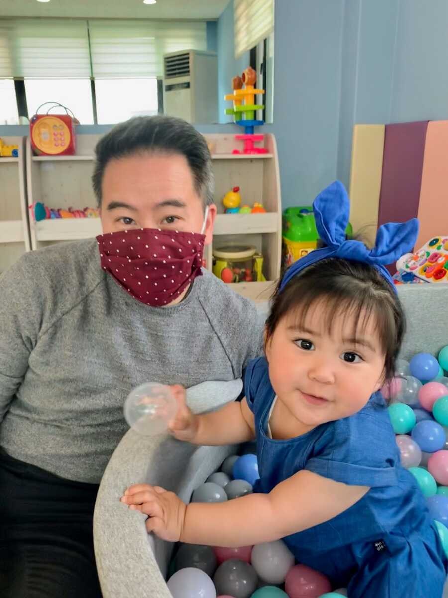 Young girl in plastic ball tub next to her future father