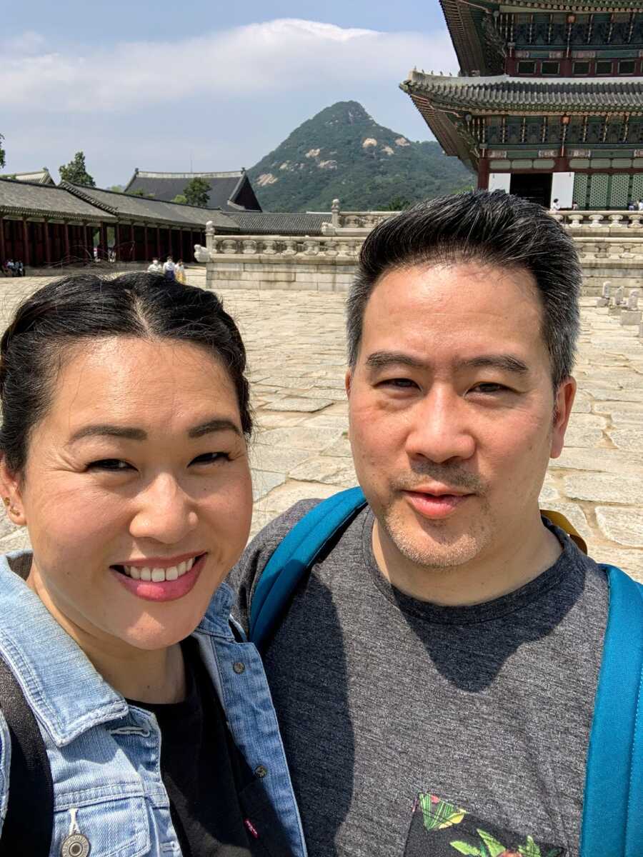 Husband and wife take selfie while visiting Korea to adopt little girl.