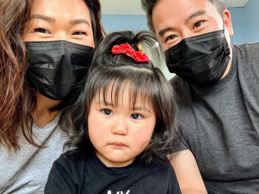 Mother and Father in surgical masks with future adopted daughter