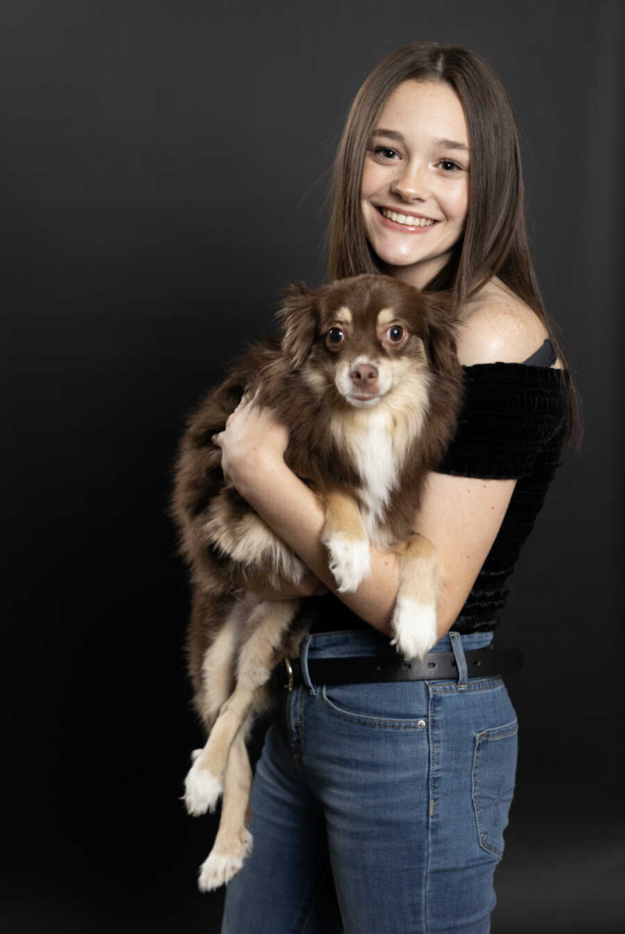 Adopted teen holds pet dog and poses for professional photo.