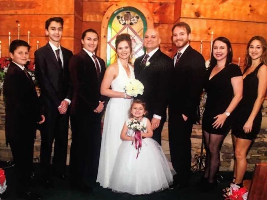 Husband and wife standing at their wedding with kids from previous marriages