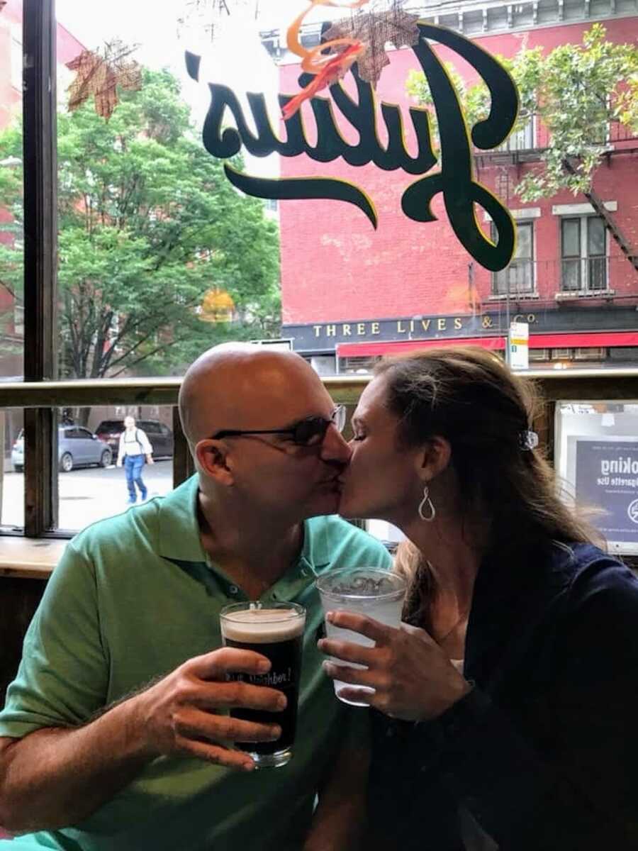 husband and wife kissing at a bar