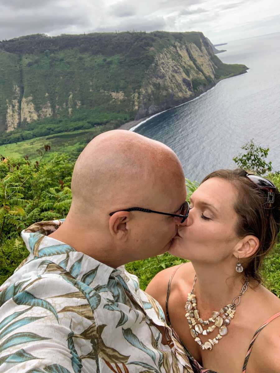 husband and wife kissing while on a hike