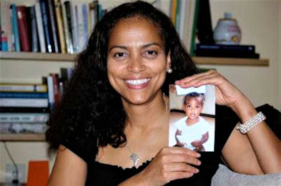 Adoptive mother holding a picture of her Ethiopian daughter and smiling