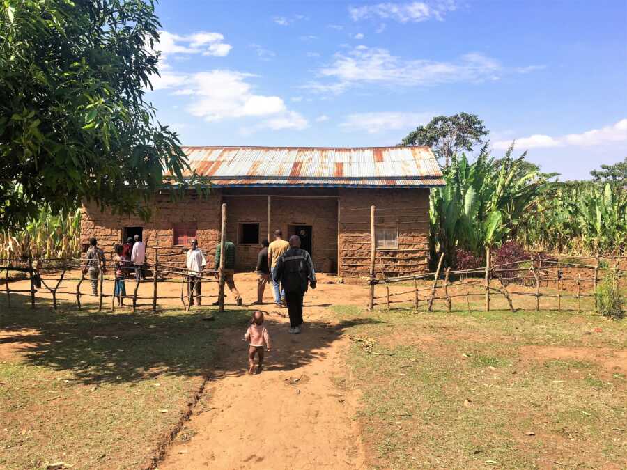 Mud house in Ethiopia with adults and children walking in from the main entrance