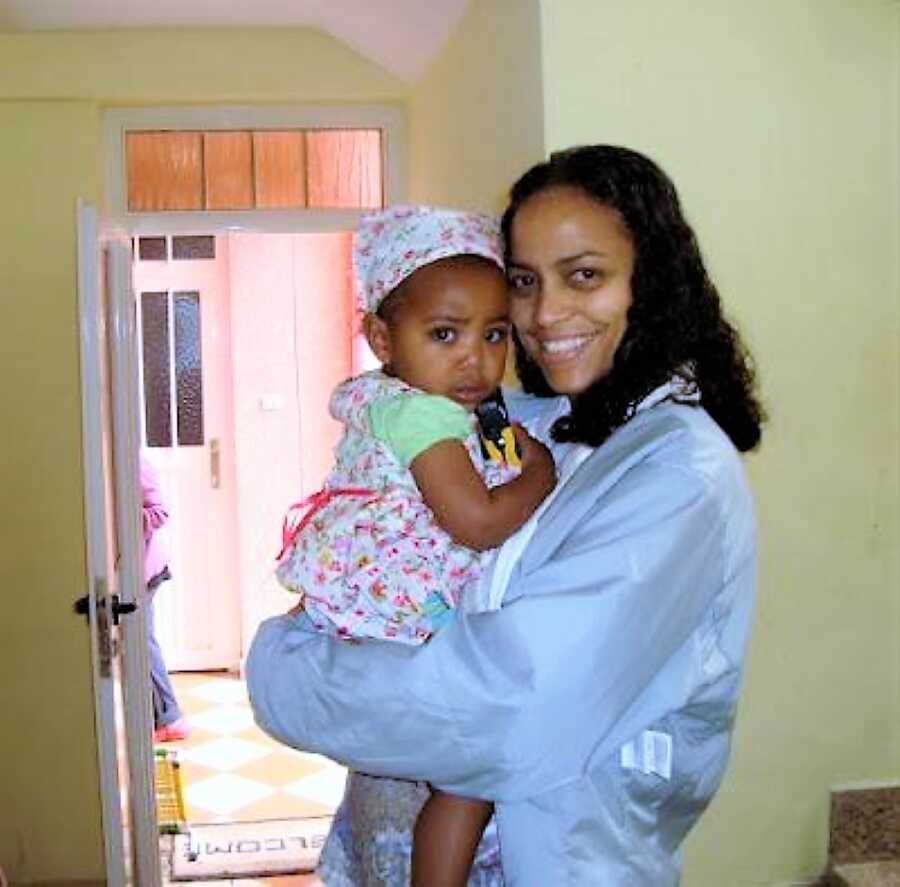 Adoptive mother holding her toddler daughter in her arms