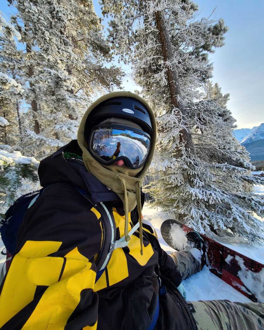 Woman sitting on snowy hill while snowboarding