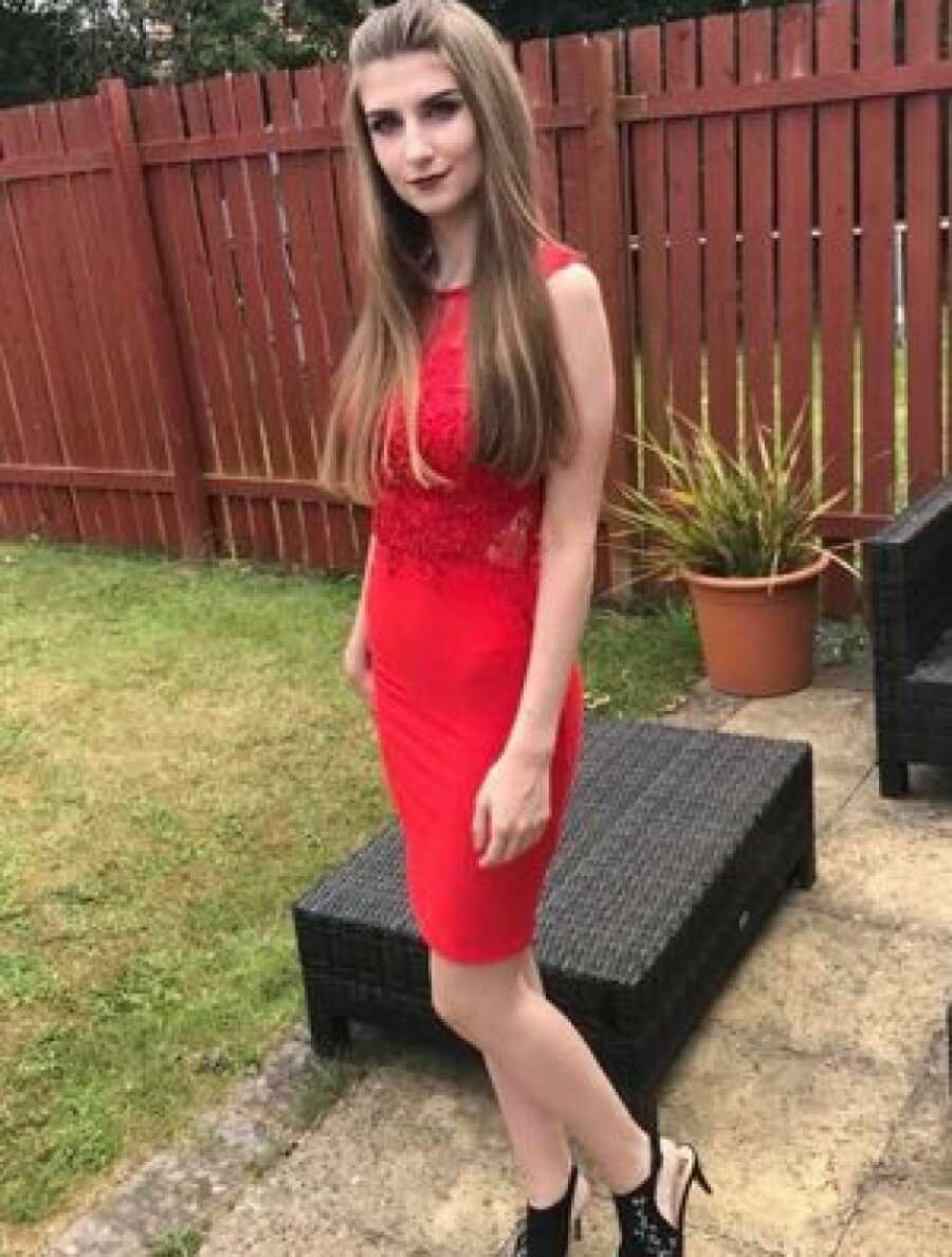 autistic woman in a red dress, wearing a lot of makeup, in a back yard