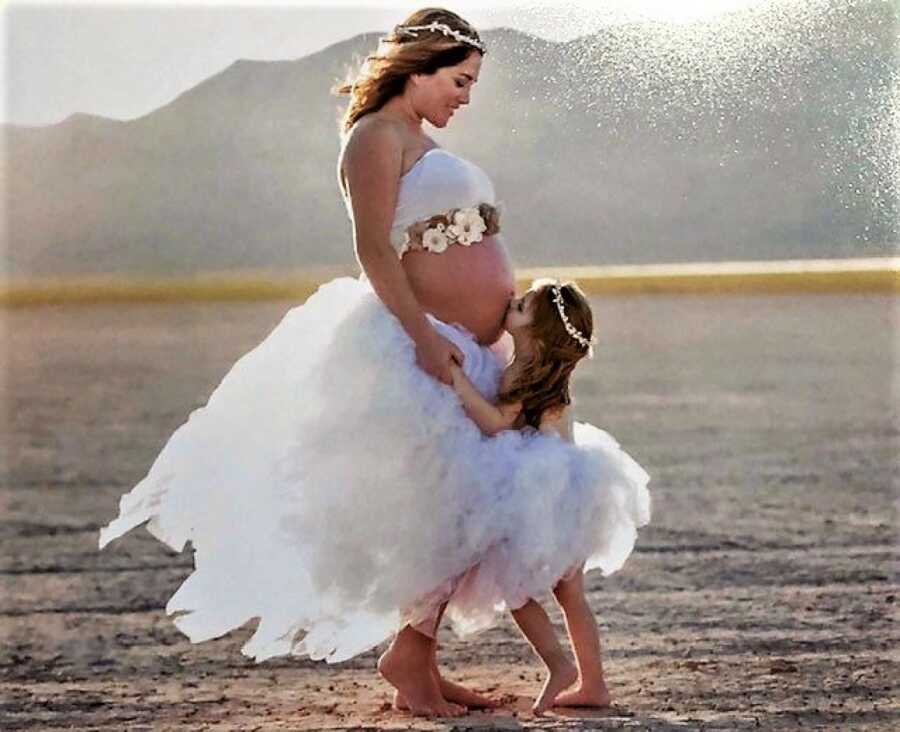daughter kissing her mom's pregnant belly