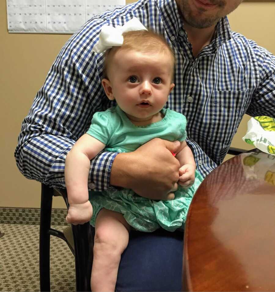 Baby daughter sitting on her father's lap