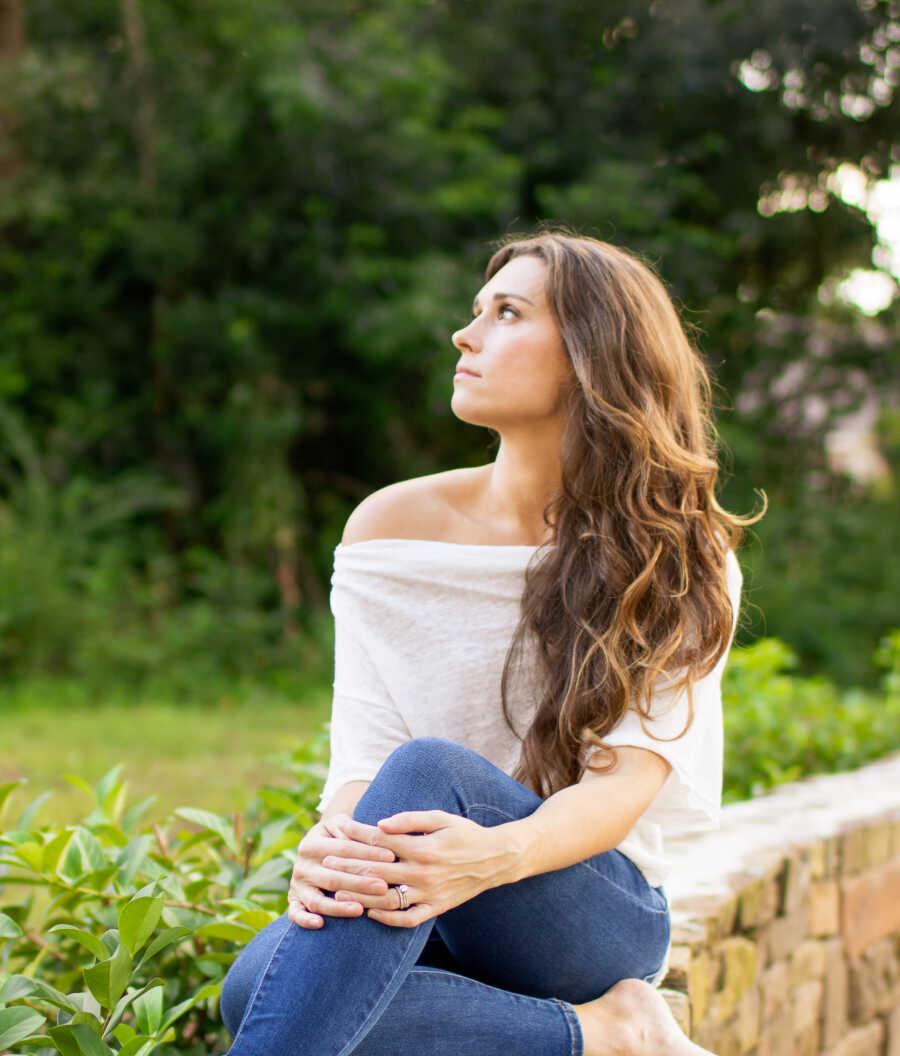 stepmother sitting on stone wall looking to the side