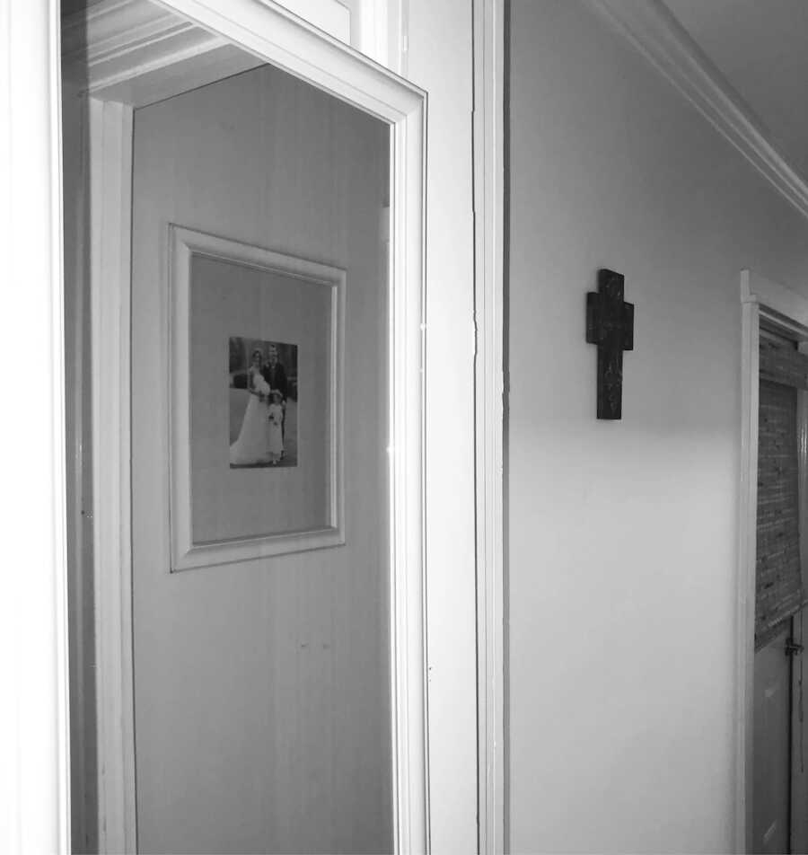 black and white photo of wall with photo and cross on it 