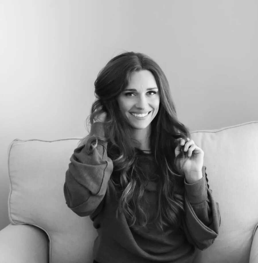 black and white photo of woman smiling with hand on hair 