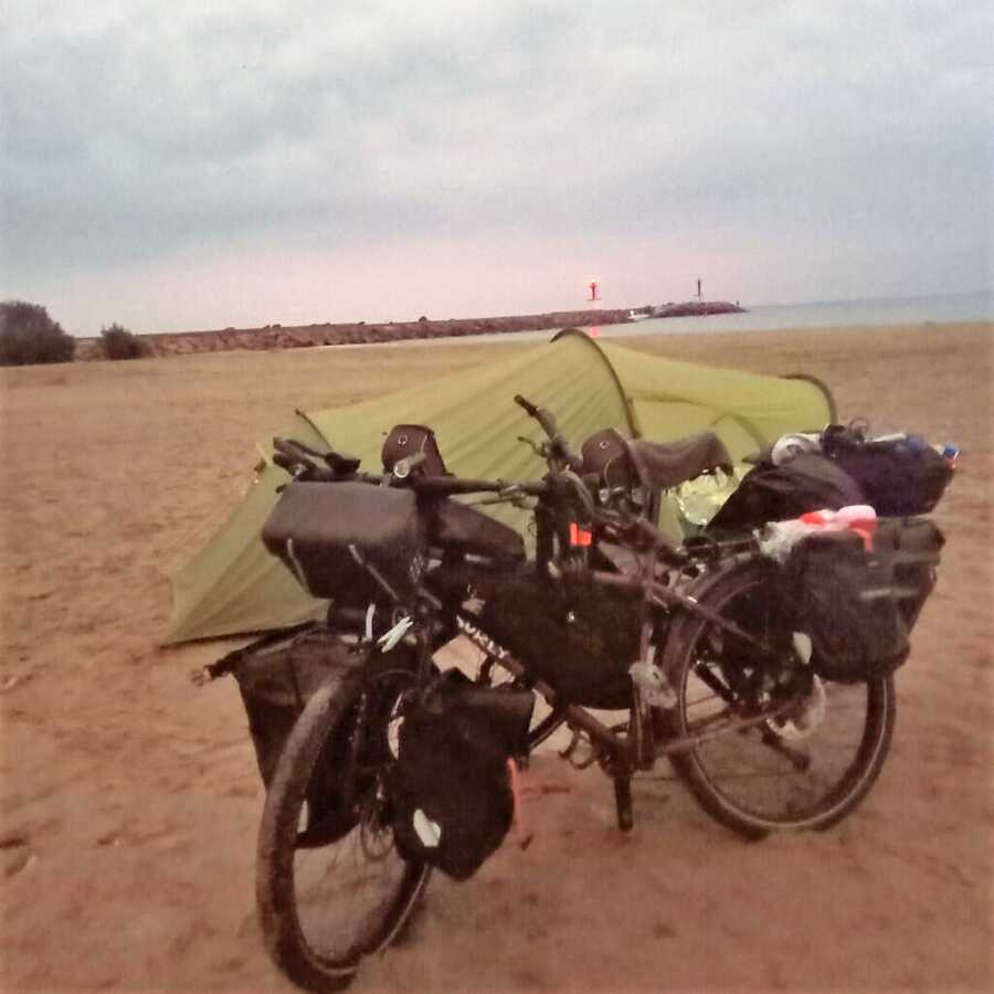 couple camping on beach with bikes