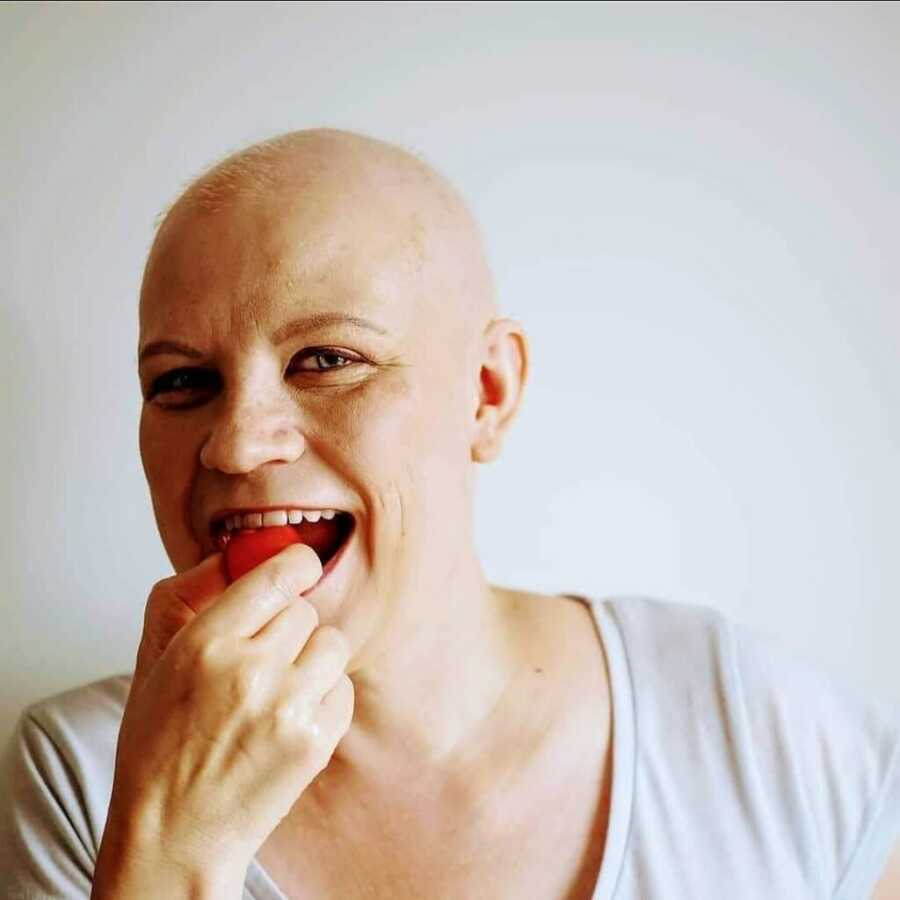 woman with cancer eating a strawberry