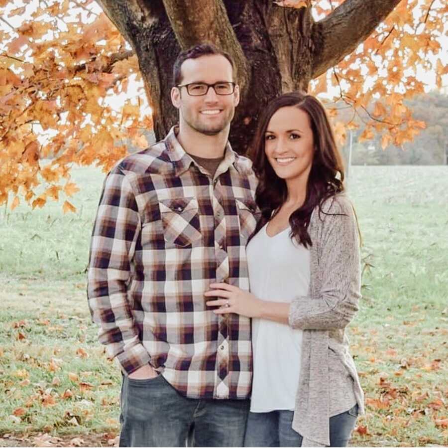 Husband and wife smiling together in front of tree