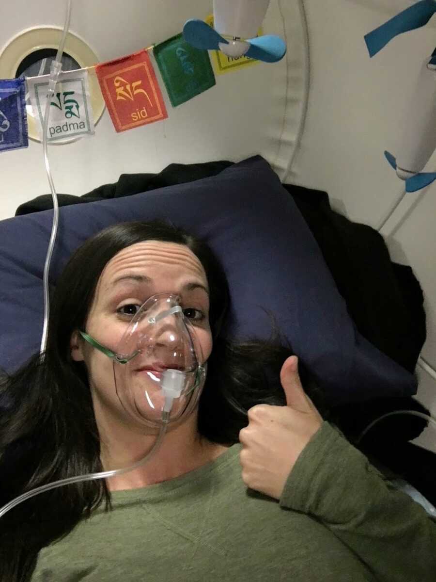 Woman lying on bed with oxygen mask over face