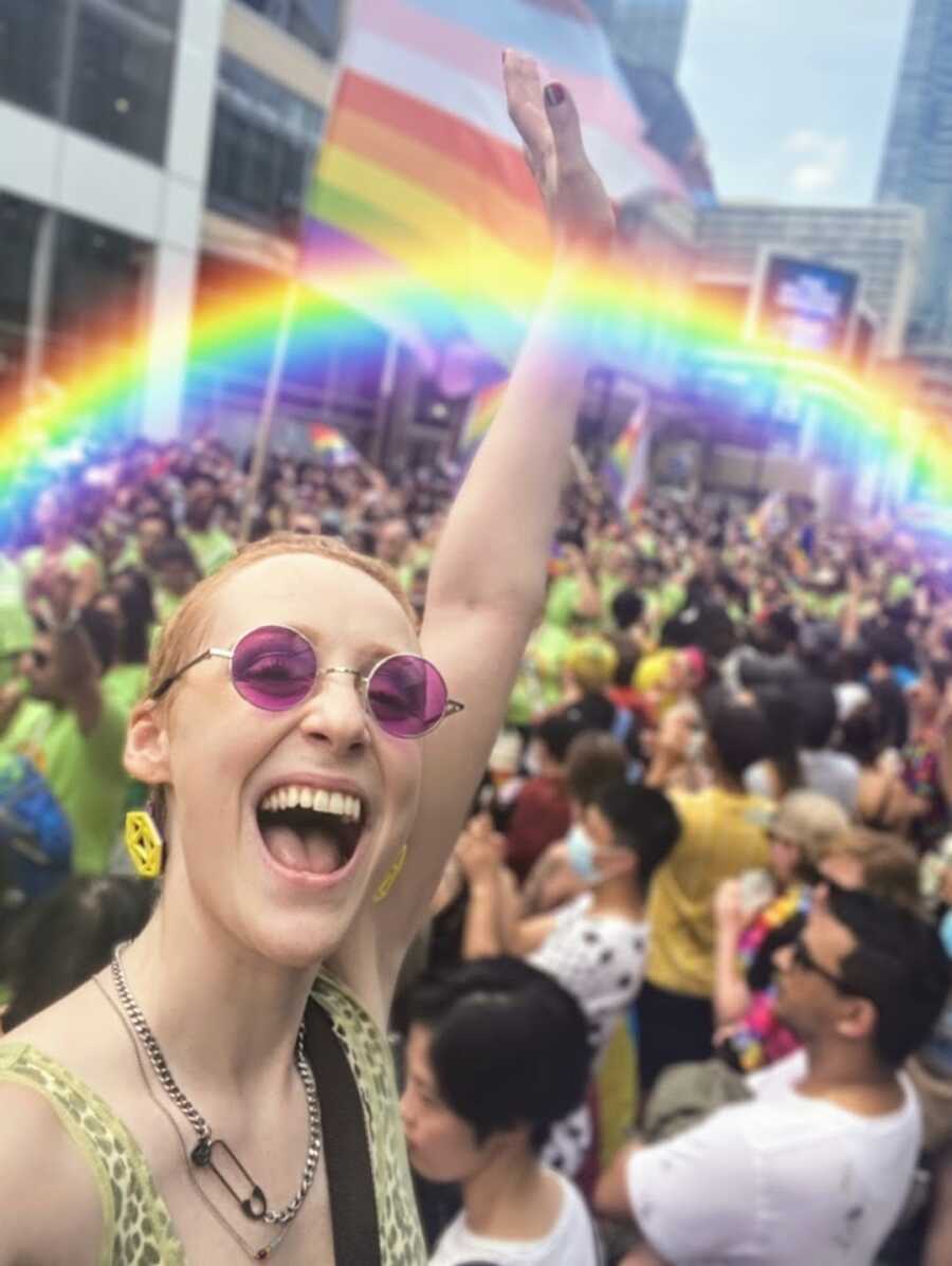 Nonbinary person at pride with a rainbow