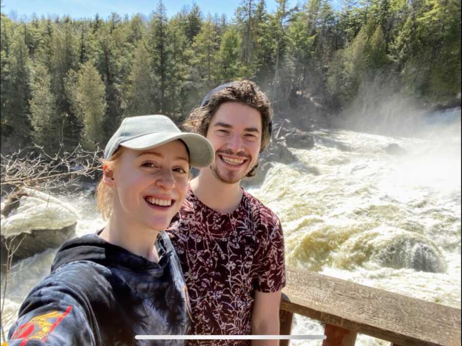 Girlfriend and boyfriend standing in front of waterfall
