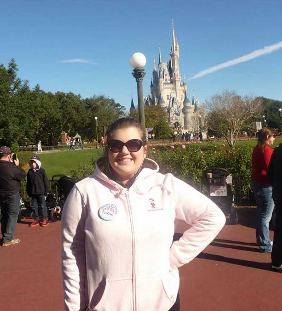 woman in sweatshirt in Disney in front of a castle