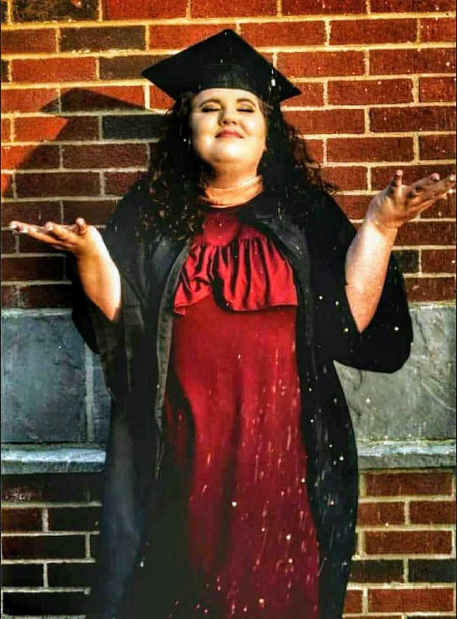 woman in graduation cap and gown with her eyes closed