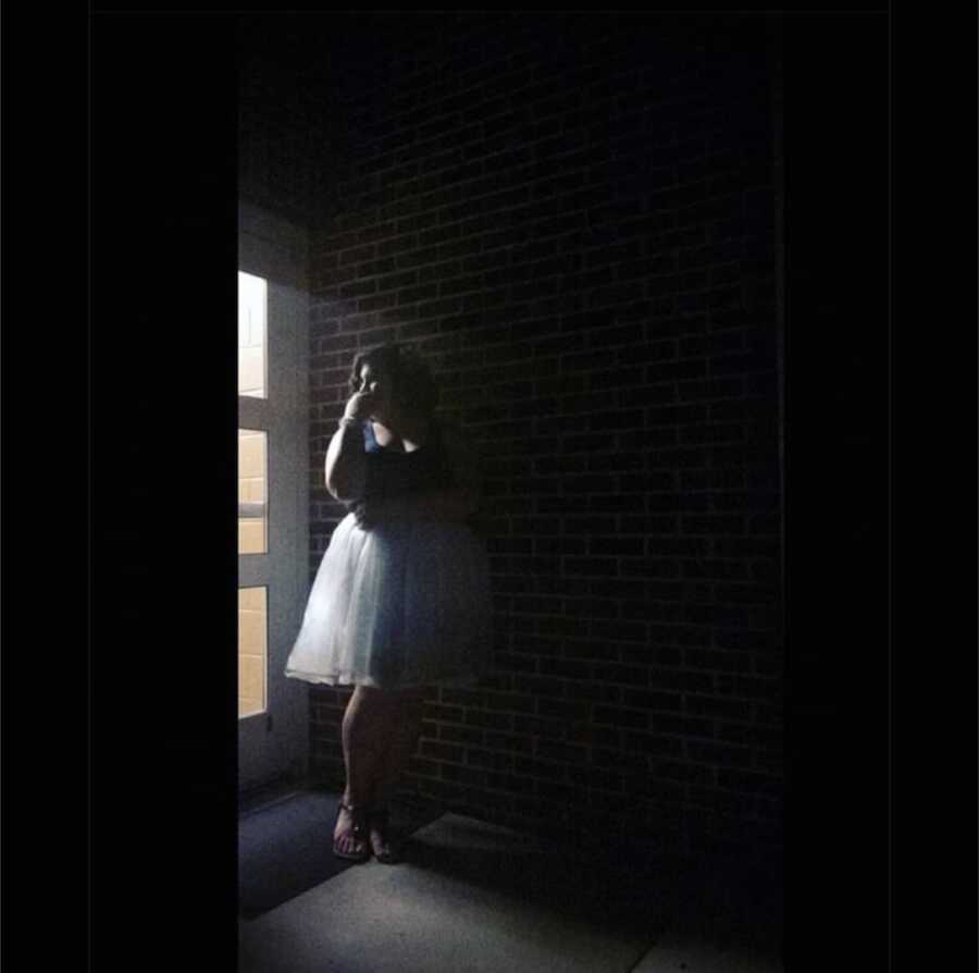 woman in a dark room wearing a puffy dress and staring out the window