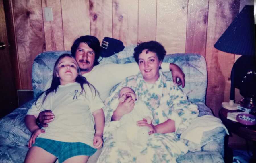 mother, father, daughter, and baby son sitting on couch together