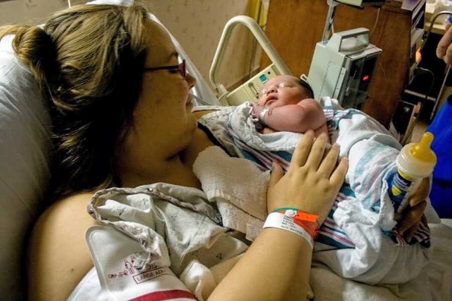 woman in hospital bed holding swaddled newborn boy