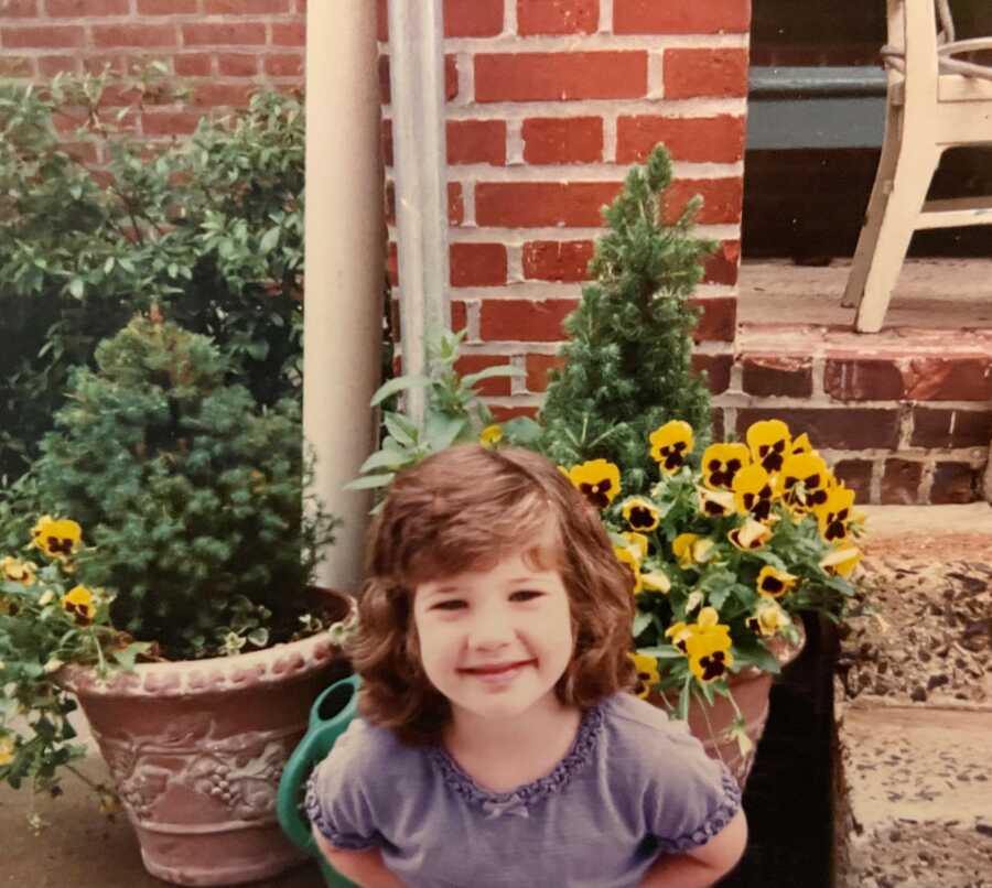 little girl sitting in front of flowers