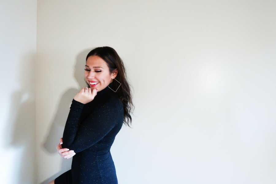 woman in all black posing against a wall