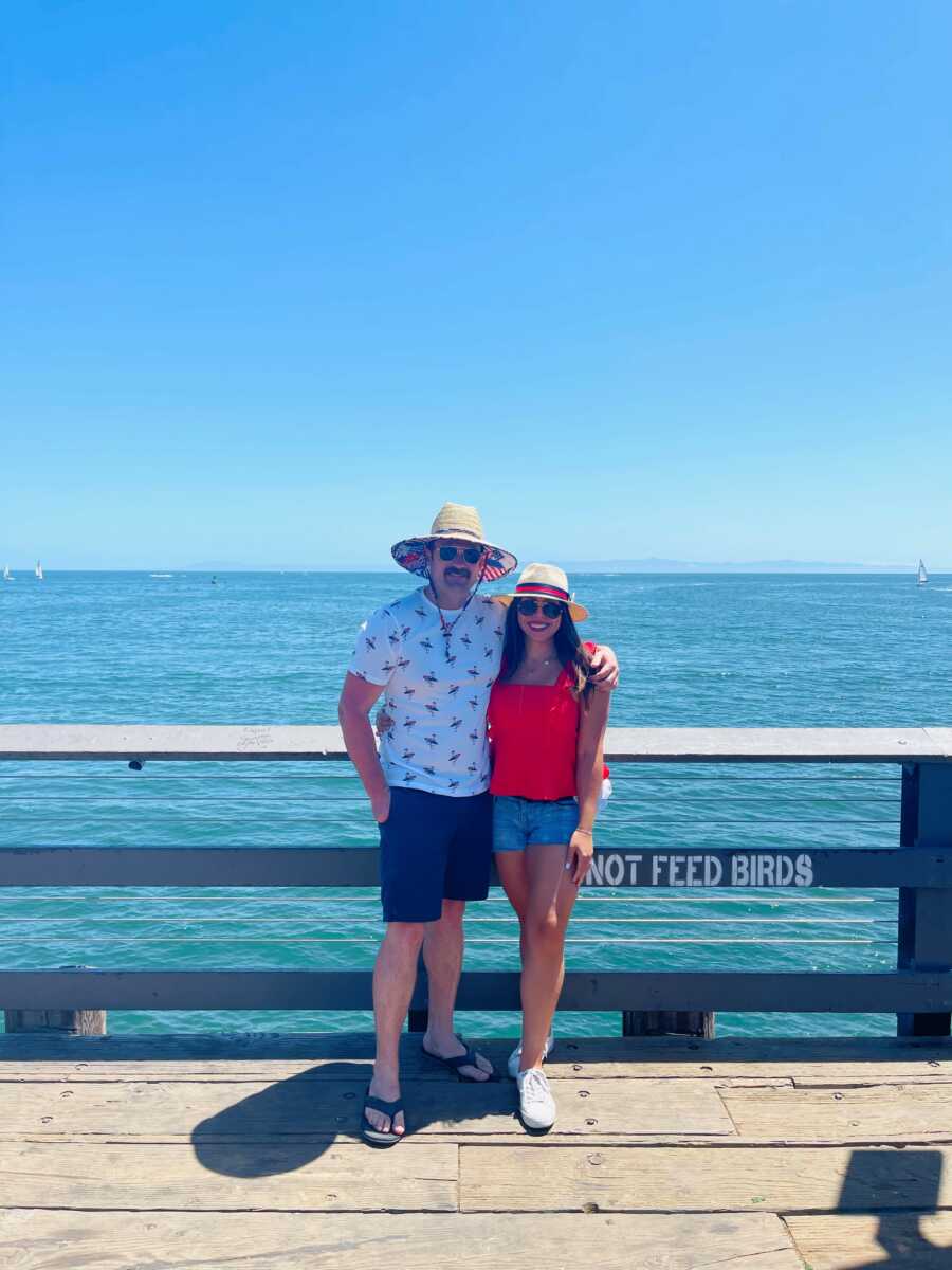 couple taking a picture in front of a beach