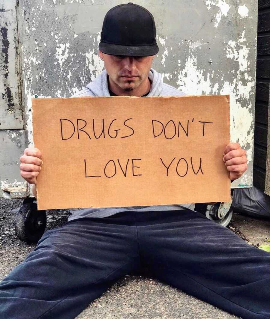 Man holding up a sign stating 'drugs don't love you'