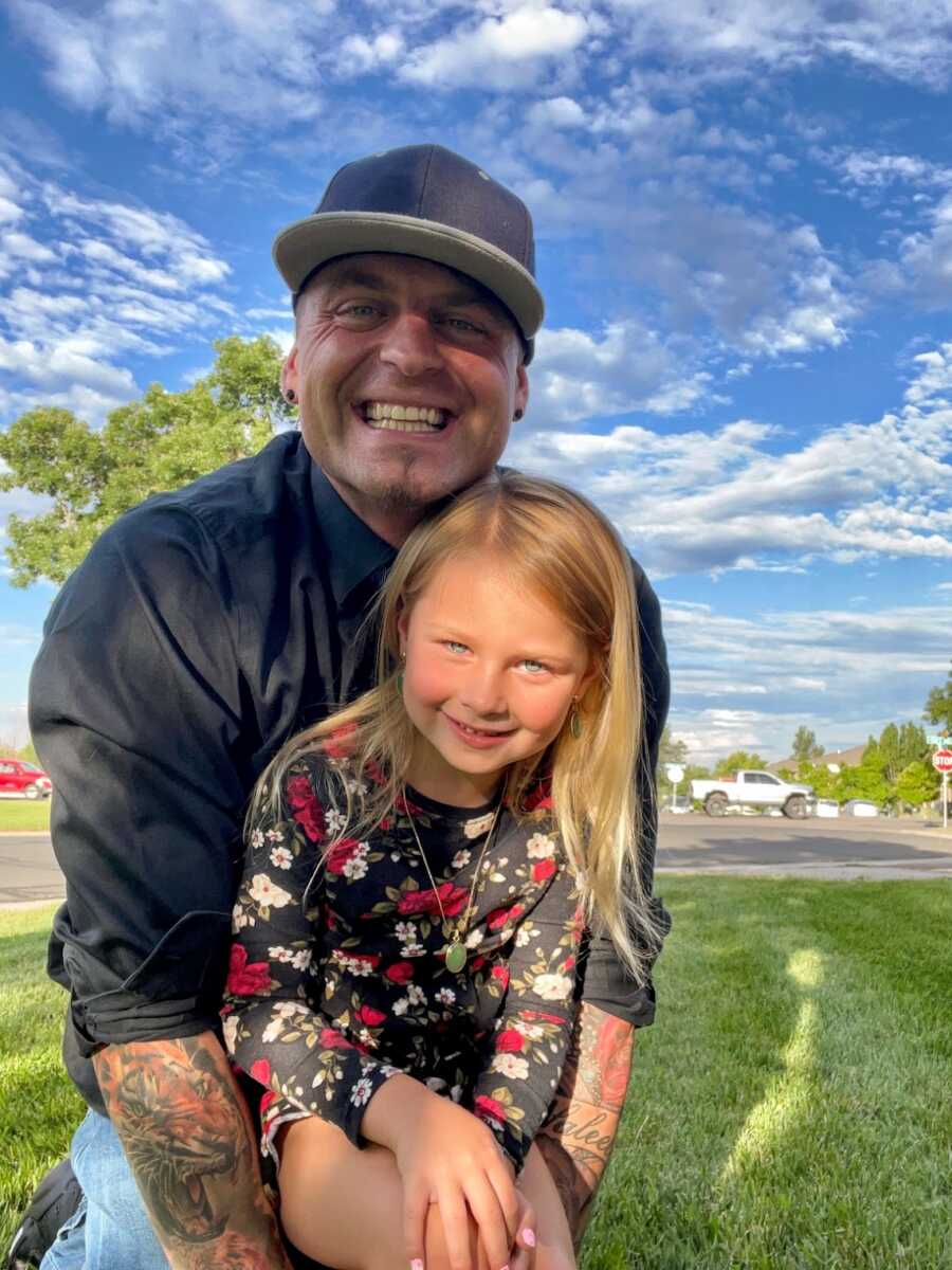 Recovered drug addict sitting outside with his daughter