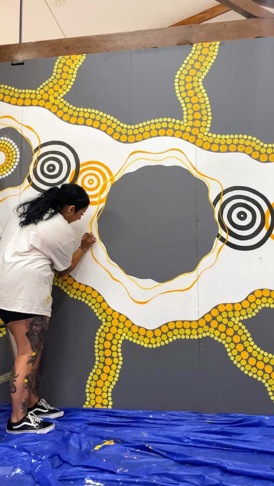 Aboriginal woman working on aboriginal painting 