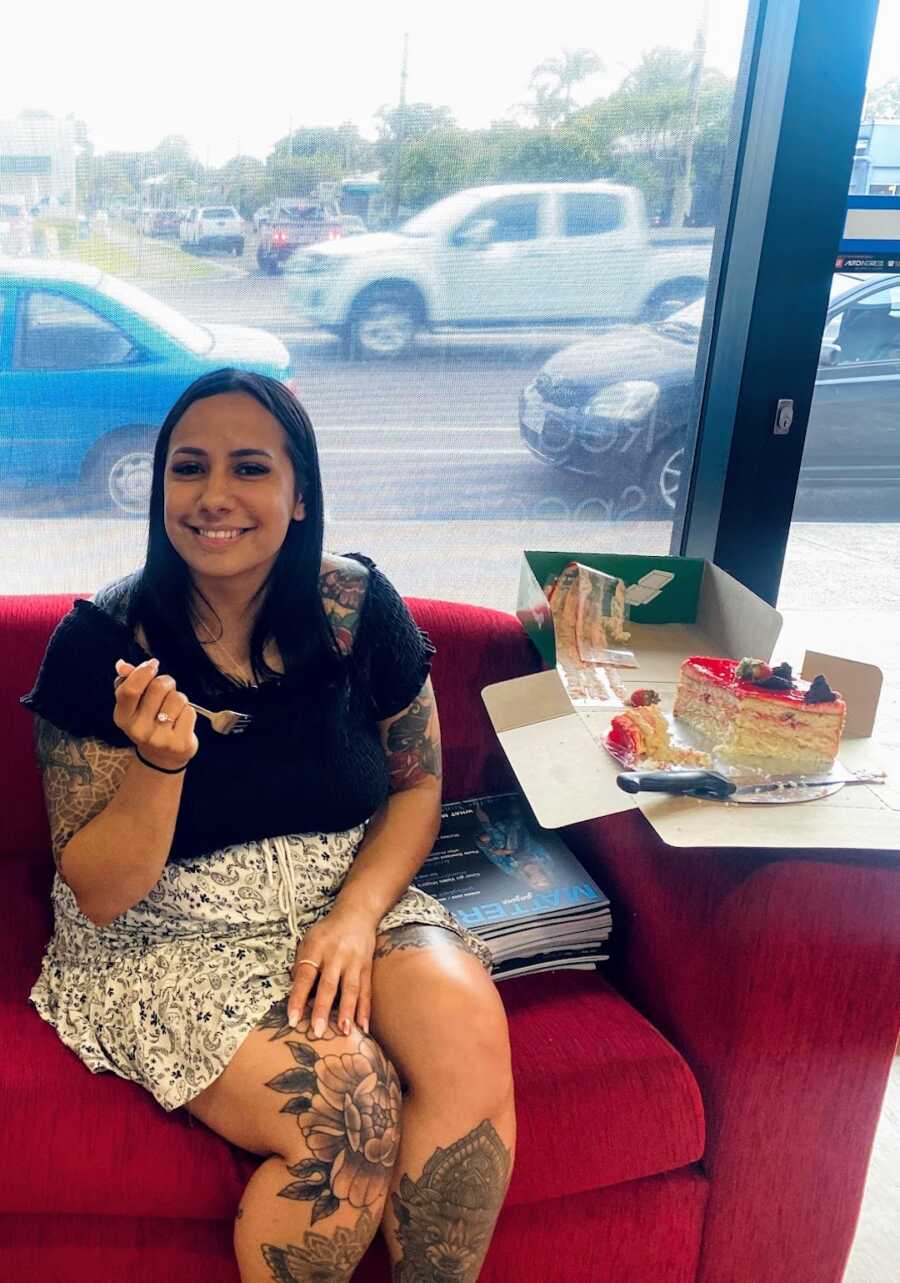 Aboriginal woman sitting next to a box of cake with a fork in hand